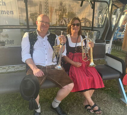 Franz und Heike Hofer sitzen mit ihren Instrumenten wartend auf einer Bank