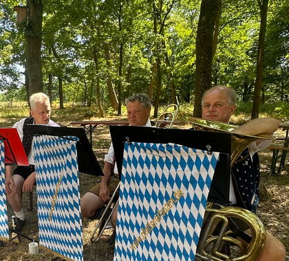 Die Pfatterer Buam sitzen gemütlich im Schatten unter Bäumen